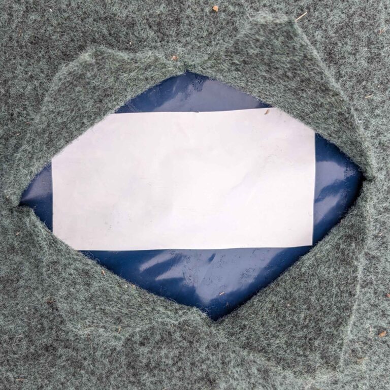 Klebeband auf blauer Barrierefolie, darüber ein Vlies