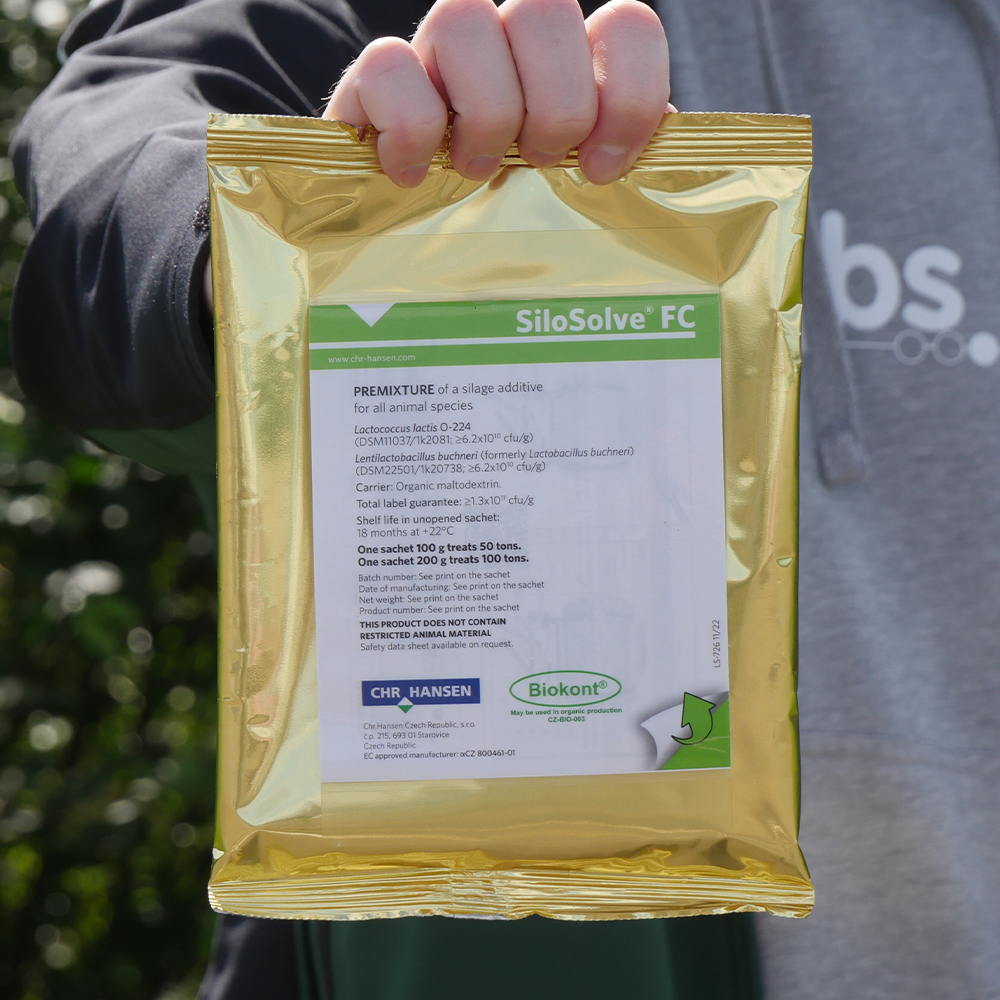 Nahaufnahme einer Person, die einen goldenen Beutel des Siliermittels SiloSolve FC in der Hand hält