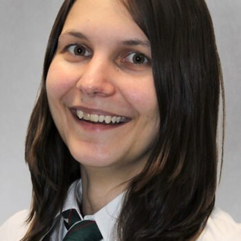 Nahaufnahme einer Frau, die lächelt, mit schulterlangen braunen Haaren, frontal fotografiert