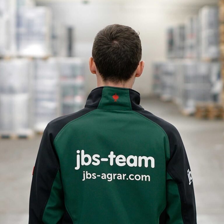 Braunhaariger Mann, er trägt eine jbs-team Jacke teils in grün und teils schwarz